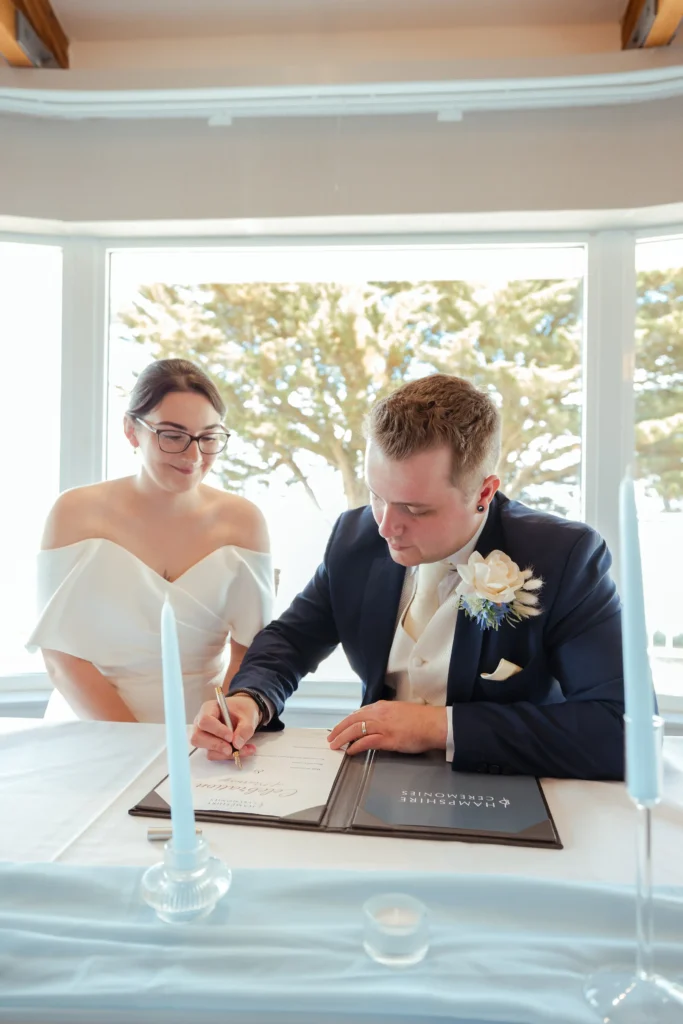 Candid wedding photo of couple signing documents in Hampshire