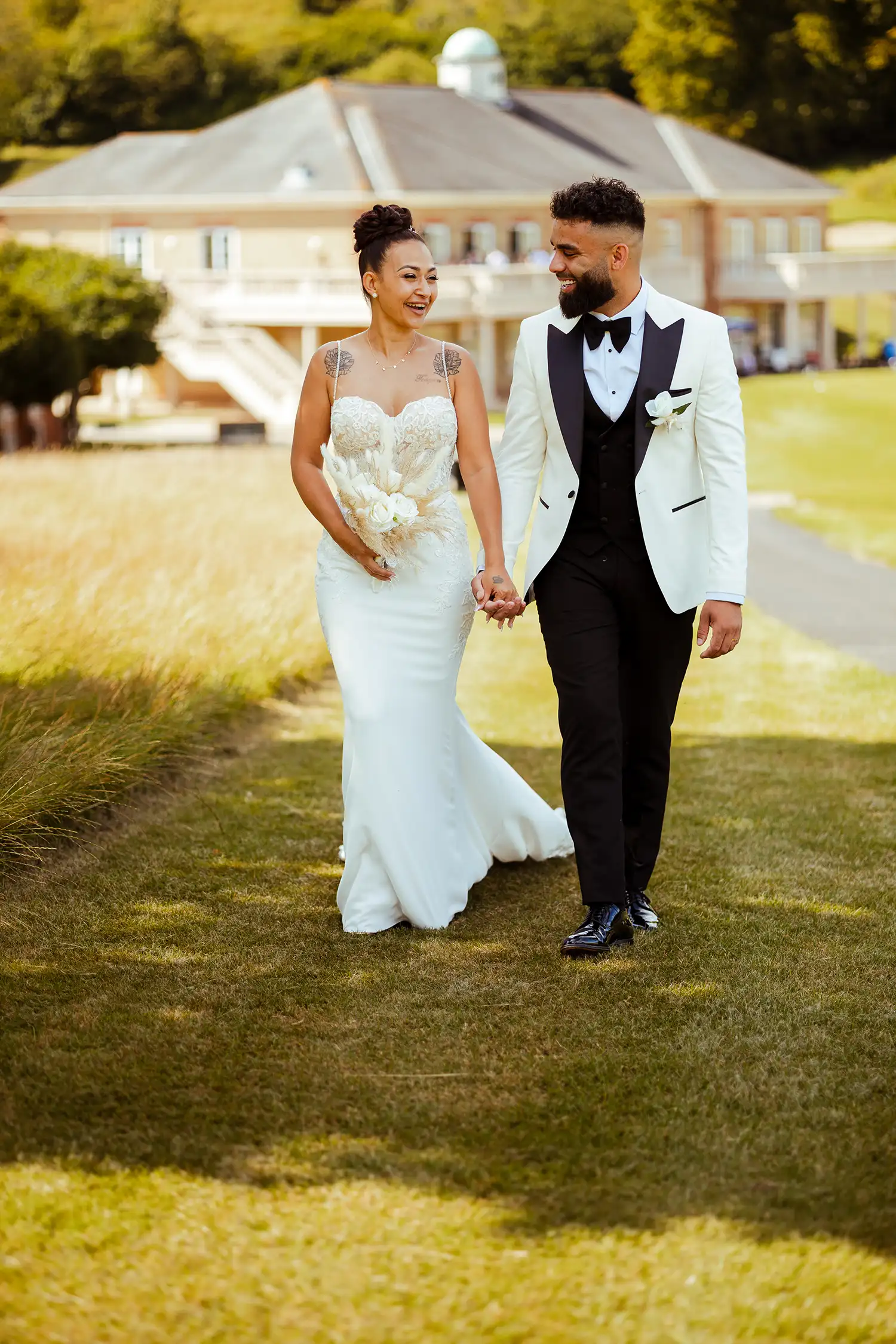 bride and groom walking on the grass with the venue as background VasPhotography