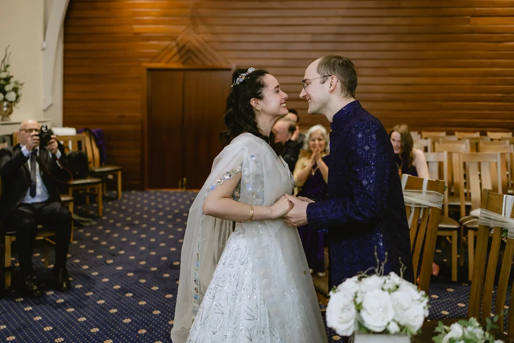 The happy bride and groom smiling at each other at the altar during their ceremony, highlighting intimate small wedding photography in Southampton by VasPhotography.