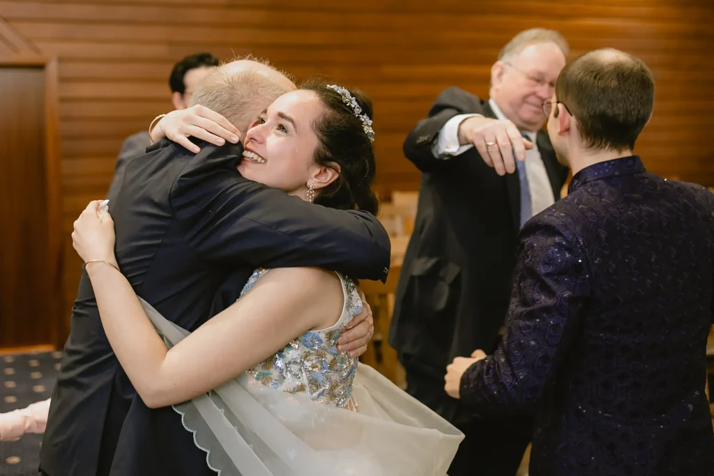 A smiling bride hugging a wedding guest during the congratulations, showcasing the emotional highlights of small wedding photography in Southampton by VasPhotography