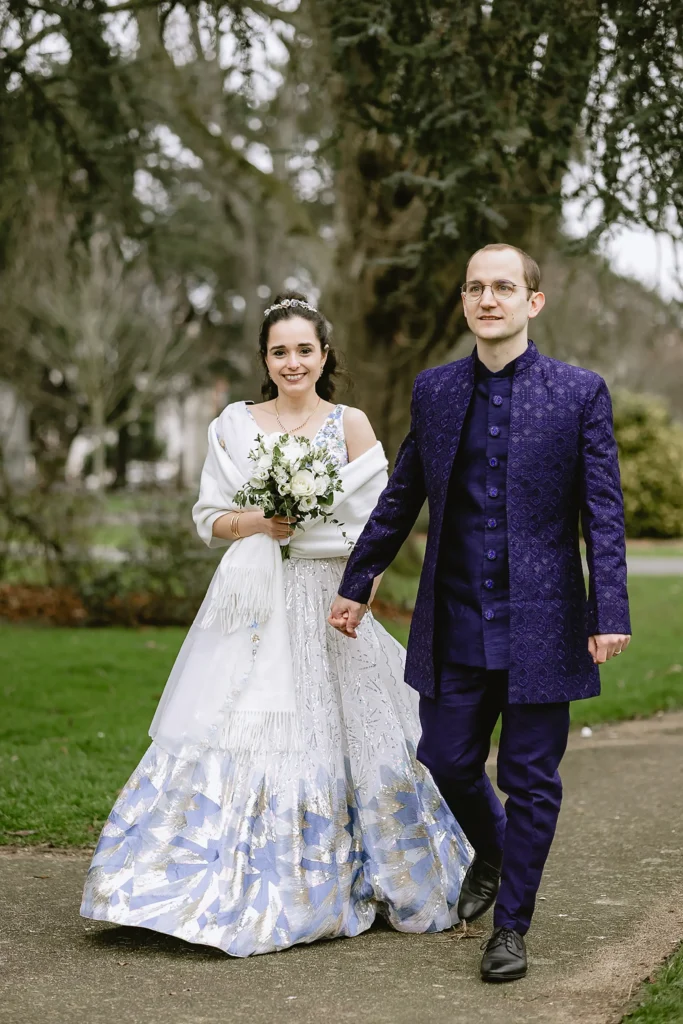 A newly married bride and groom holding hands, smiling, and posing for portraits outdoors against scenic stone walls and garden pathways, captured beautifully by VasPhotography specializing in small wedding photography in Southampton