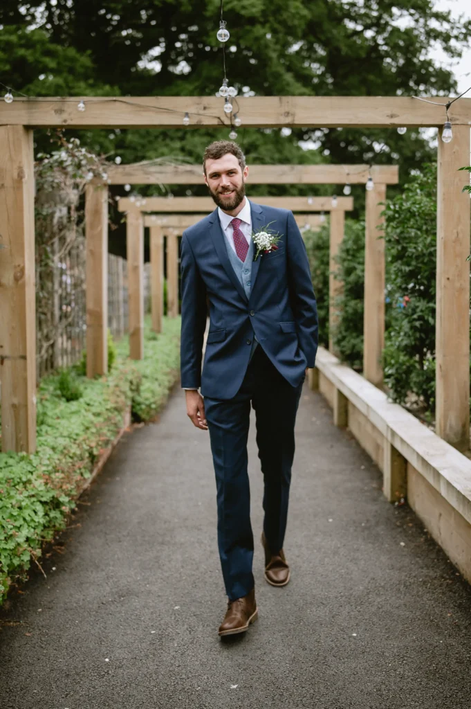 groom walking and looking in the camera at The Angel Hotel, Alton, Hampshire — candid wedding photography by VasPhotography