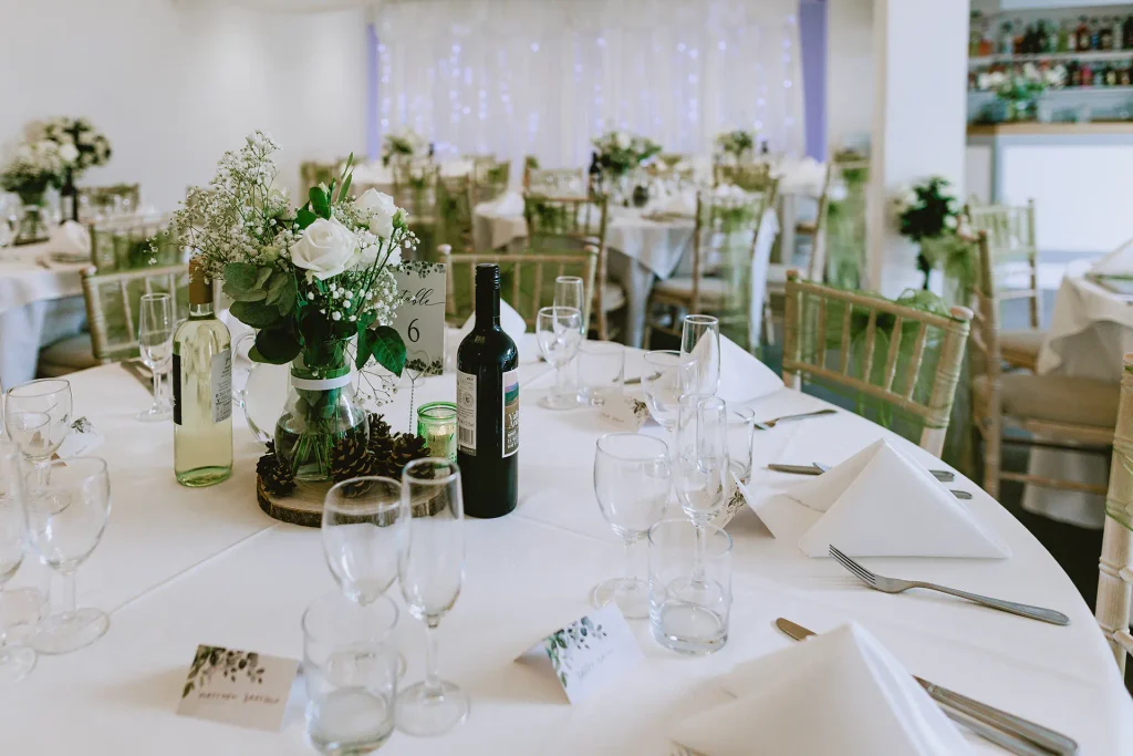 Wedding reception room dressed with green organza sashes and rose centrepieces at The Angel Hotel, Alton