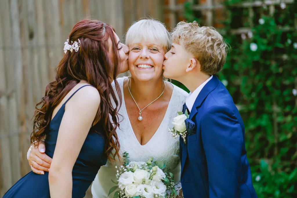 grandkids kissing the bride in the gardens at The Angel Hotel , Alton , Hampshire