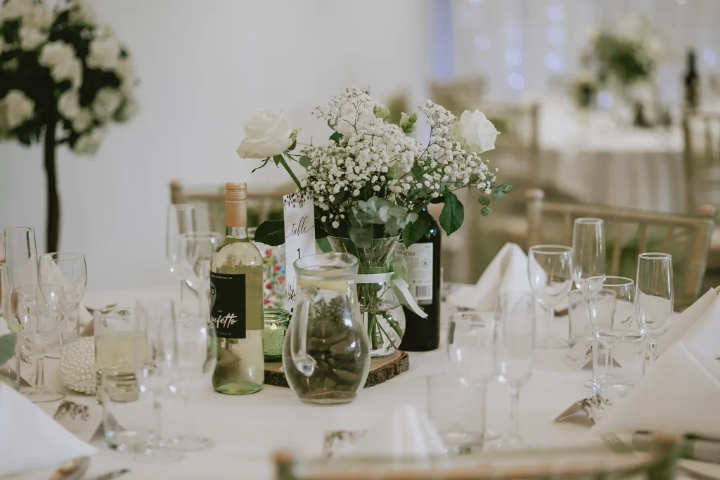 Wedding reception room dressed with green organza sashes and rose centrepieces at The Angel Hotel, Alton